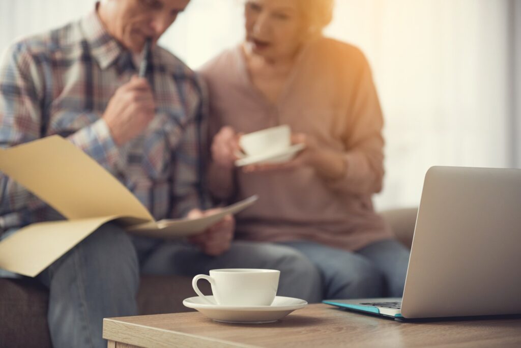 Older couple reviewing paperwork together with a laptop