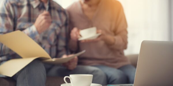 Older couple reviewing paperwork together with a laptop